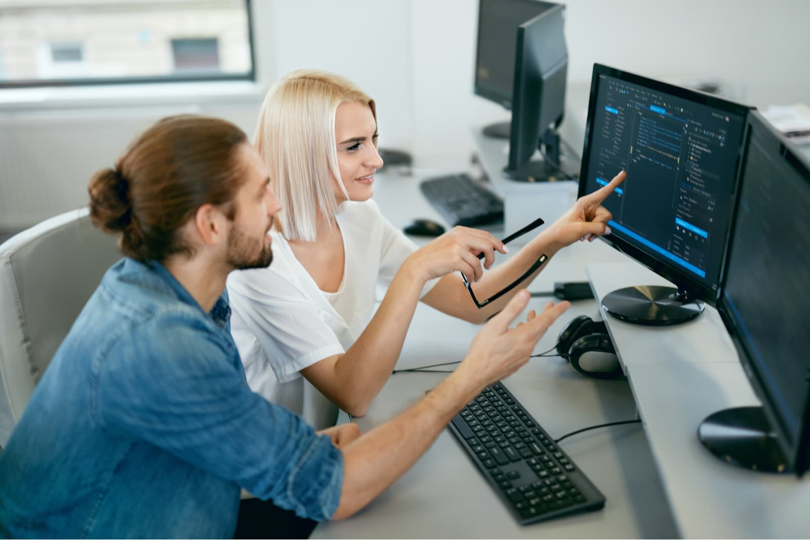 Ein Mann und eine Frau sitzen vor einen Bildschirm mit Code
